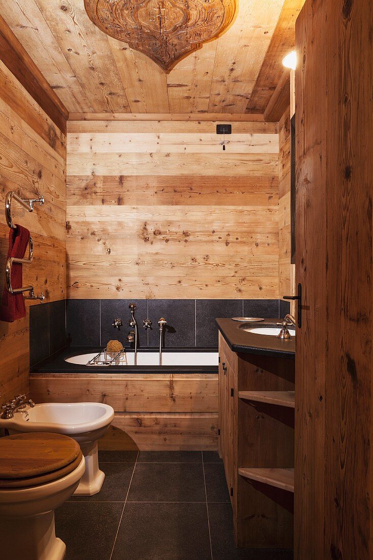 Wände, Decke und Mobiliar aus Naturholz kombiniert mit schwarzen Schieferfliesen im rustikalen modernem Badezimmer