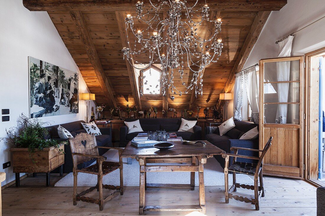 Table, hand-crafted chairs and impressive chandelier in attic living room