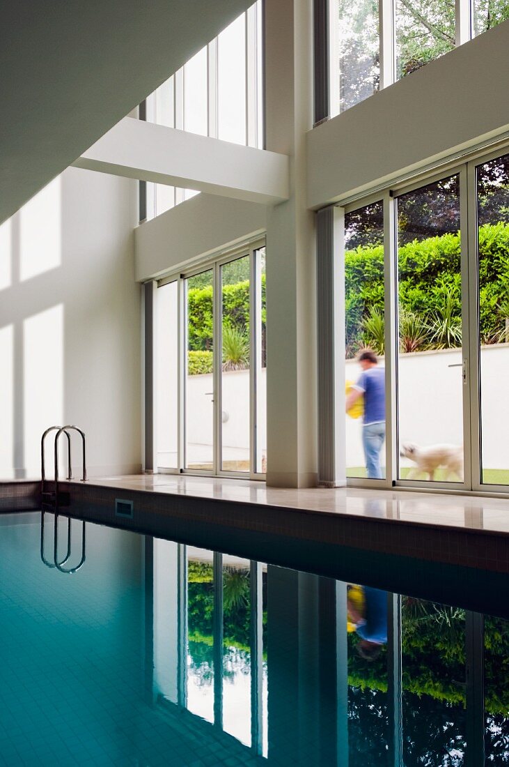 Indoor-Pool in zeitgenössischem Wohnhaus mit raumhohen Fenstern und Blick in Garten