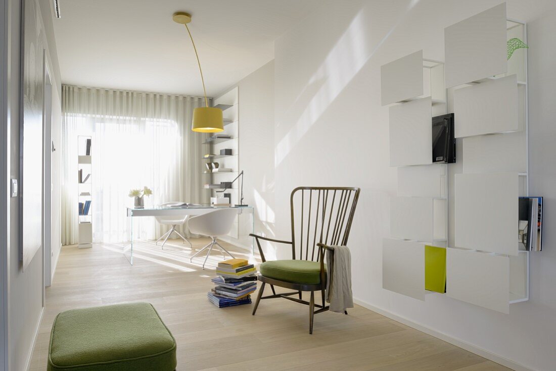 Minimalistischer, lichtdurchfluteter Arbeits- und Wohnraum mit weißem Wandregal und Vintage-Armstuhl