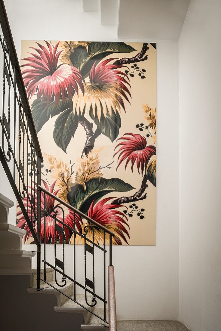 Großes, florales Bild an weisser Wand in Treppenhaus mit Jugendstil-Metallgeländer