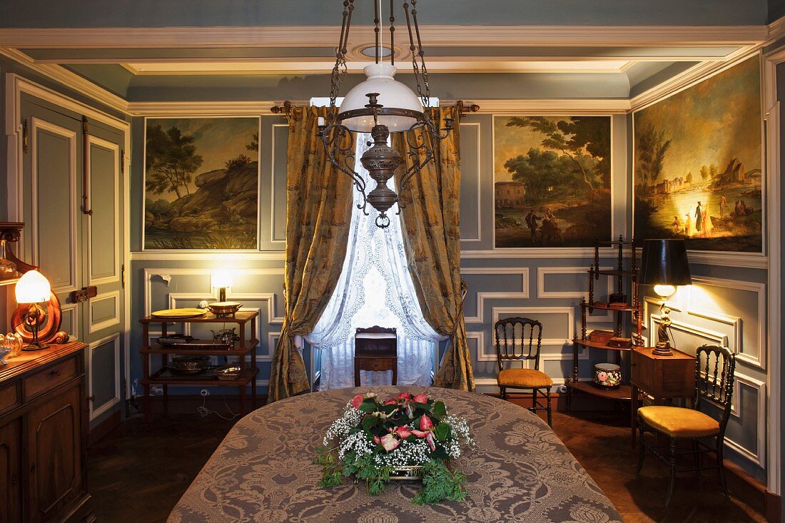Stilvoll ausgestattetes Esszimmer mit blauweisser Holzvertäfelung und historischen Gemälden