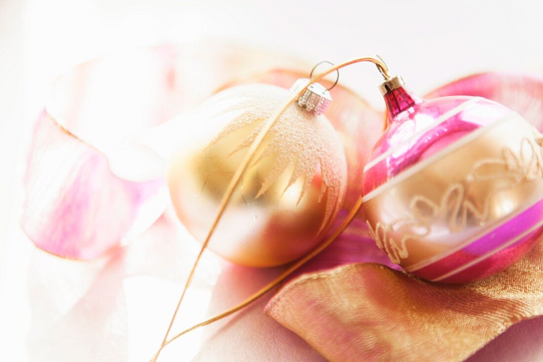 Gold and pink Christmas baubles lying on ribbon