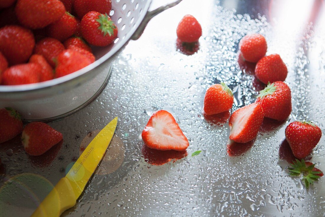 Gewaschene Erdbeeren in Standsieb auf nasser Edelstahlarbeitsfläche