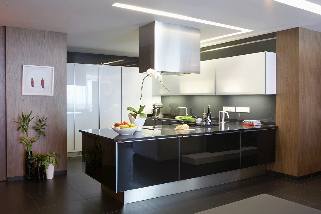 Designer-Küche mit Materialmix - Theke mit glänzender schwarzer Front unter Edelstahl Dunstabzug, weisser Hängeschrank an grauer Wand