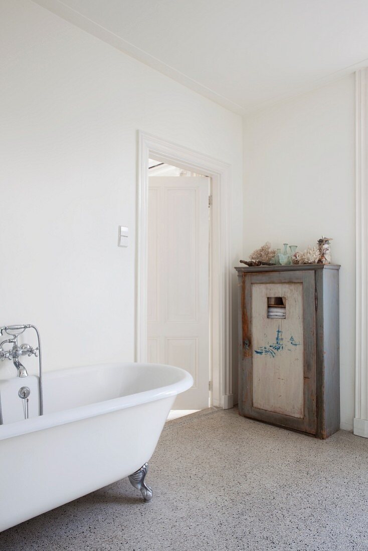 Vintage cupboard next to bathroom door; free-standing clawfoot bathtub with retro tap fittings