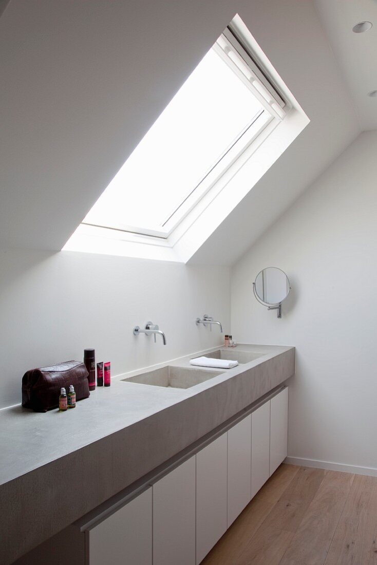 Skylight above concrete washstand with twin, integrated sinks and wall-mounted taps