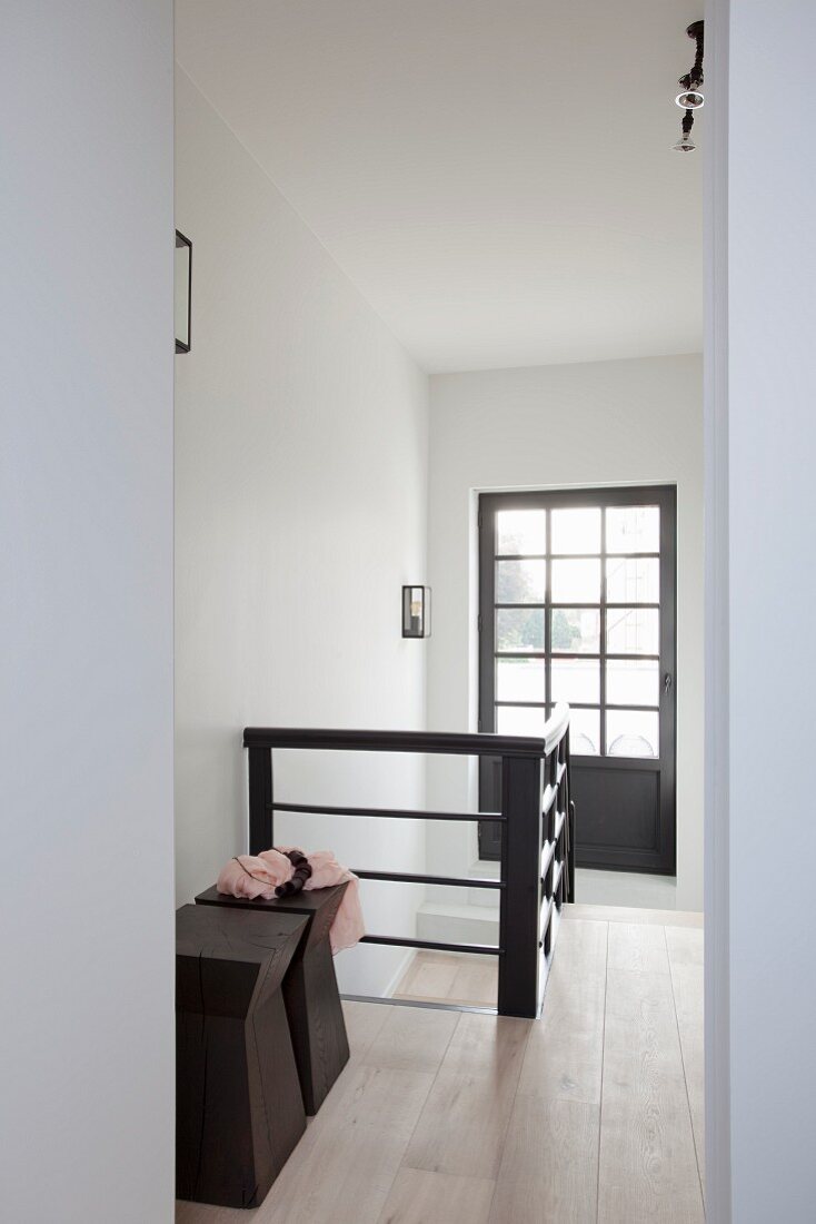 Holzhocker im Designerstil im Treppenhaus mit verglaster Tür