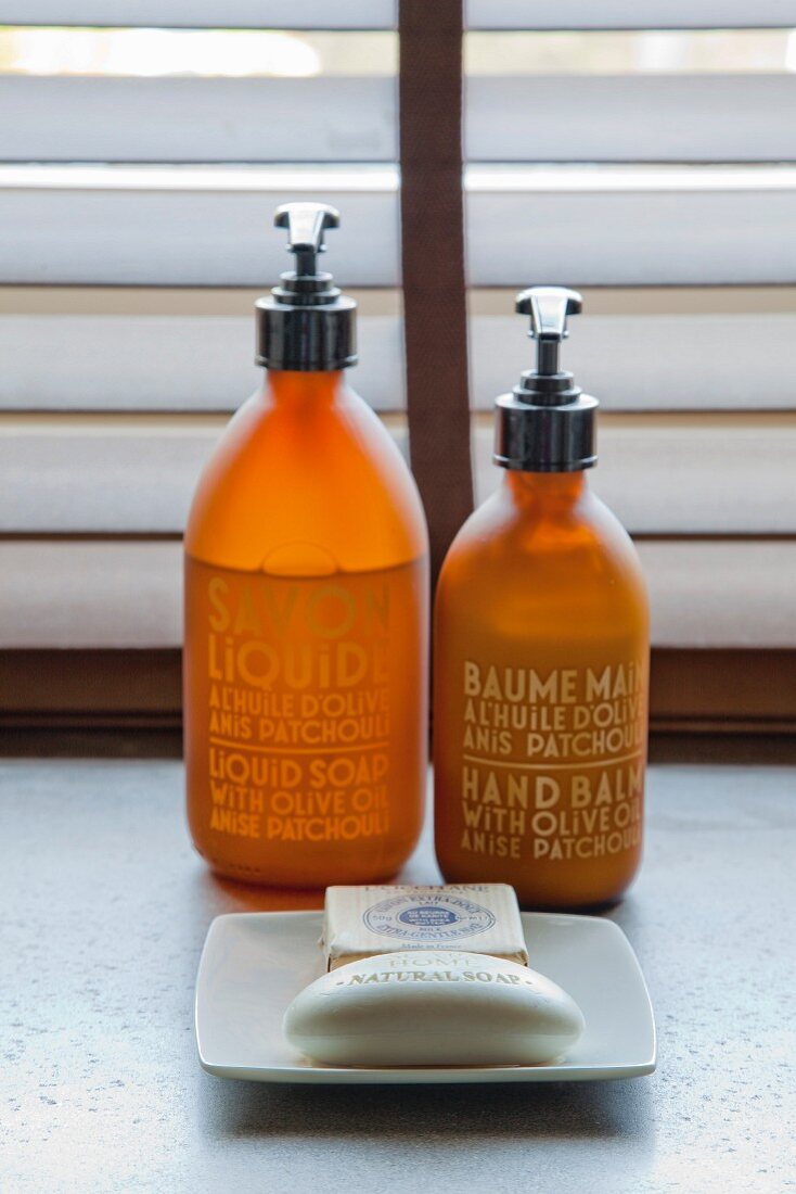 Pump-operated soap and hand lotion dispensers with gold lettering and soap dish