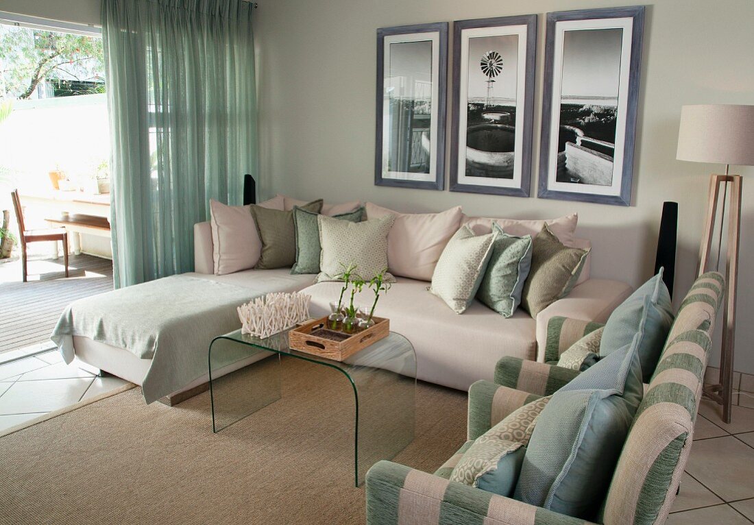 Loungebereich vor der Terrasse - Sessel, Sofa und Tagesliege um Glas-Couchtisch, an Wand gerahmte Bilder