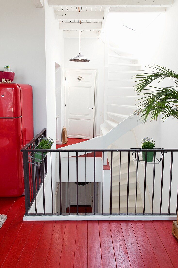 Rot lackierter Holzboden und schwarzes Metallgeländer auf Galerie in offenem Treppenhaus