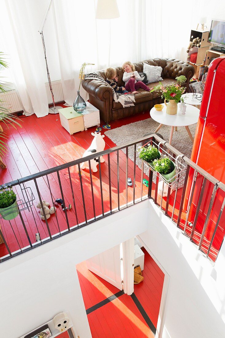 Wohnzimmer auf Galerie mit braunem Ledersofa und rot lackiertem Holzdielenboden