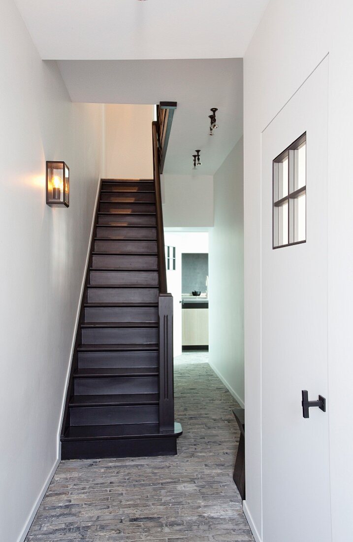 Narrow stairwell with stone floor and renovated front door in foreground