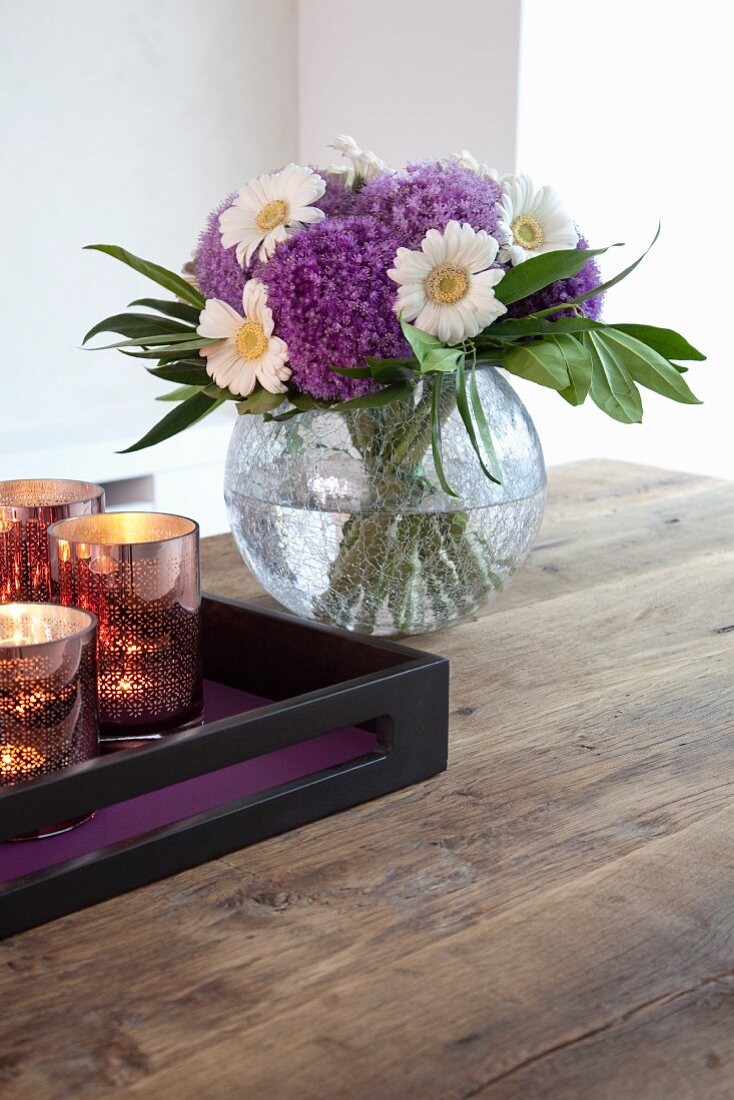 Tablett mit Teelichtgläsern und Blumenstrauss auf rustikalem Holztisch