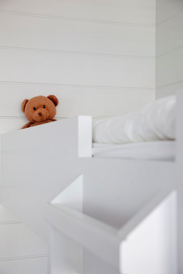 Teddy bear sitting on loft bed with ladder