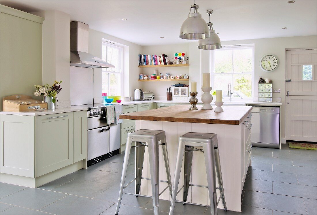 Retro, metal bar stools at free-standing island counter in open-plan, country-house kitchen