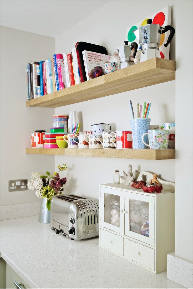 Holzregale mit Büchern und Geschirr an Wand über Küchenzeile mit Retro Toaster