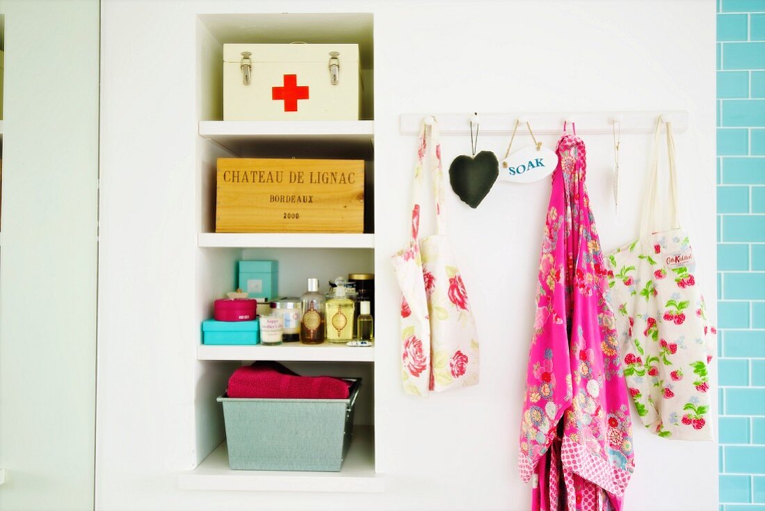 Storage boxes on shelving in niche and bags hanging from wall hooks