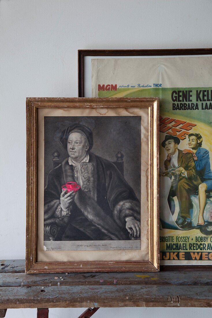 Gerahmtes Renaissance- Männerportrait und Vintage Filmposter auf rustikaler Holzbank