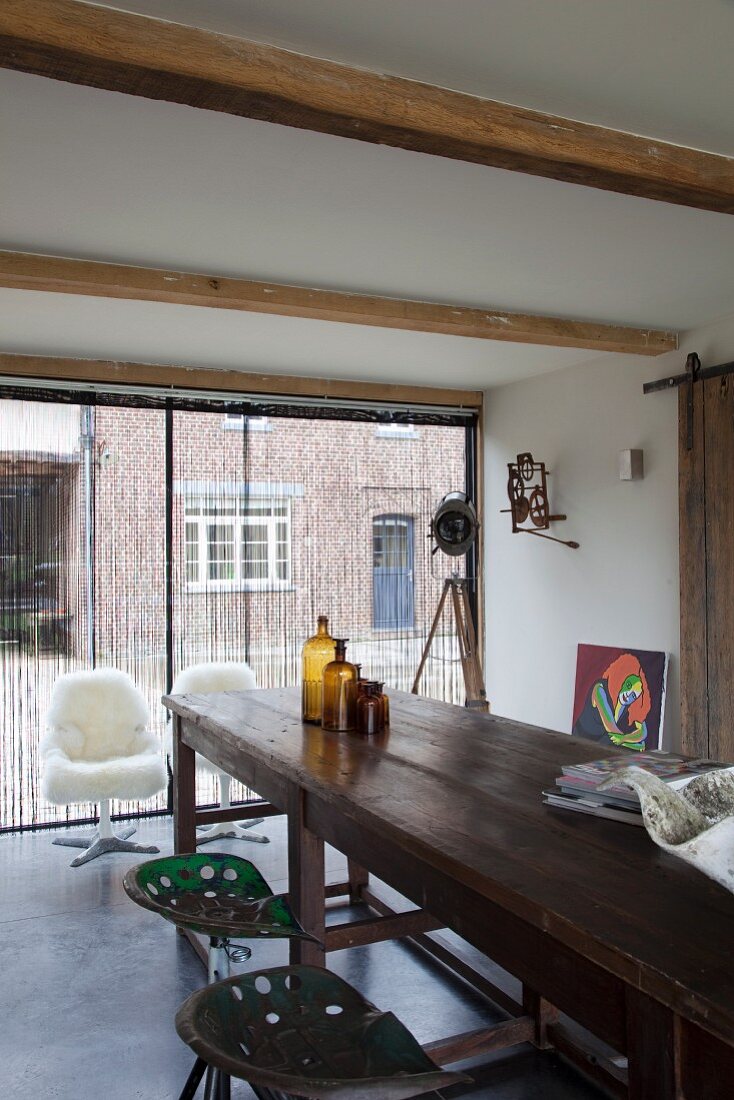 Lange Holztheke und Vintage Barhocker in renoviertem Landhaus mit Fensterfront und Retrosesseln mit Schaffell