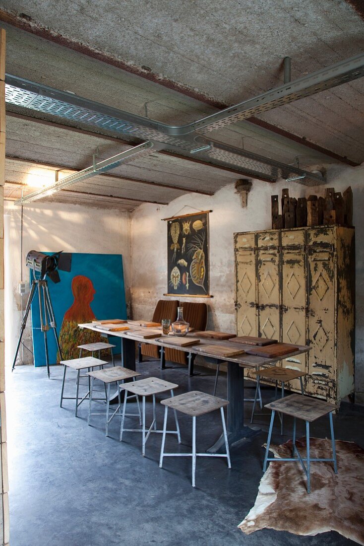 Artist's studio with simple stools, table set with wooden boards and vintage metal lockers