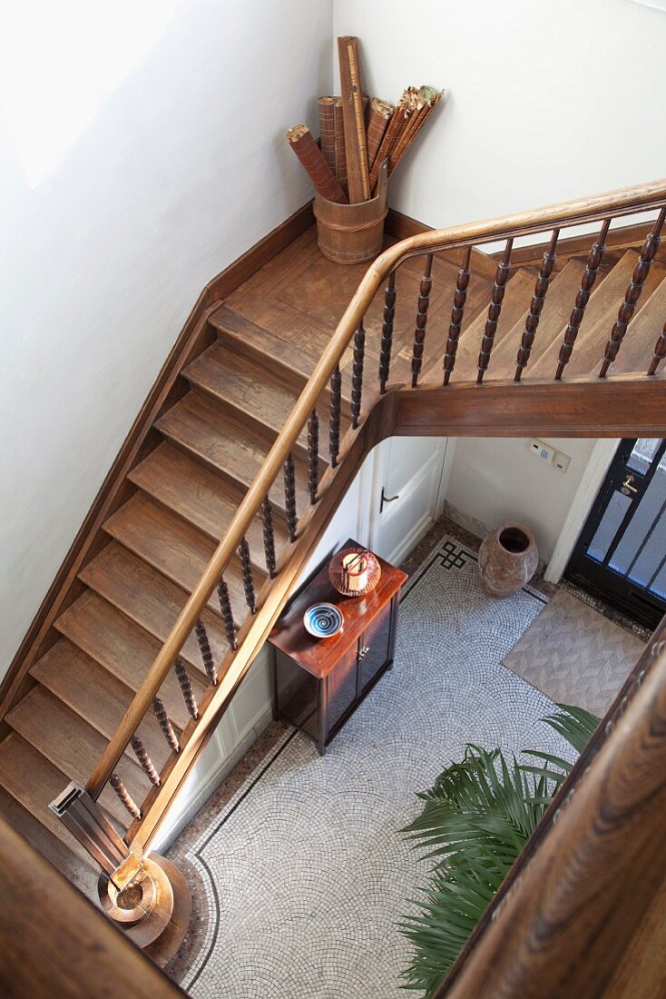 Blick ins Treppenauge auf Holztreppe mit gedrechseltem Geländer und Eingangsbereich in traditionellem Ambiente