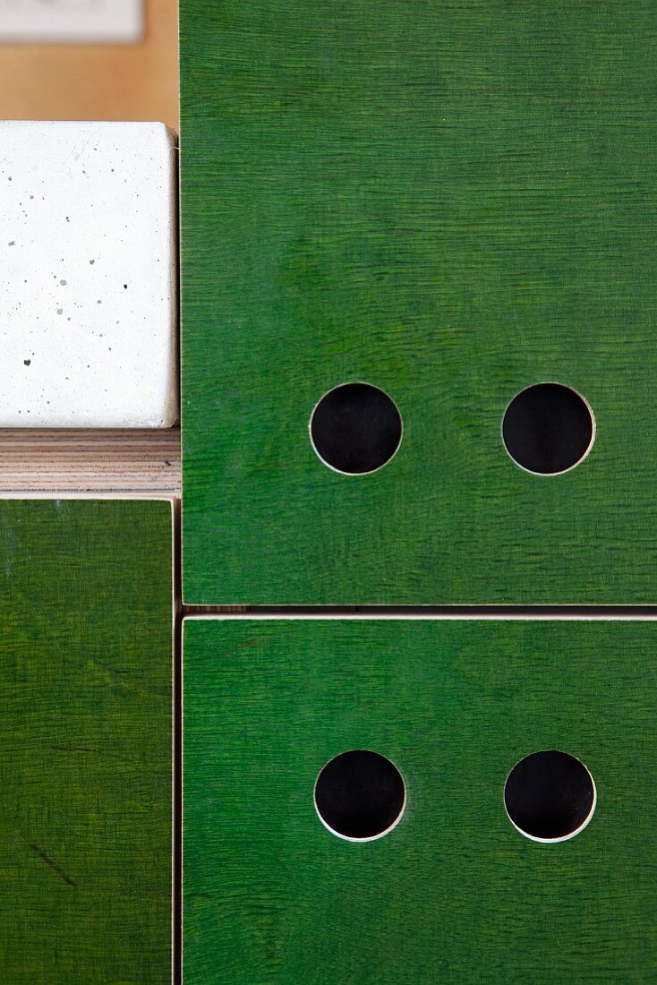 Detail of DIY kitchen cupboards with pull holes in doors stained grass green