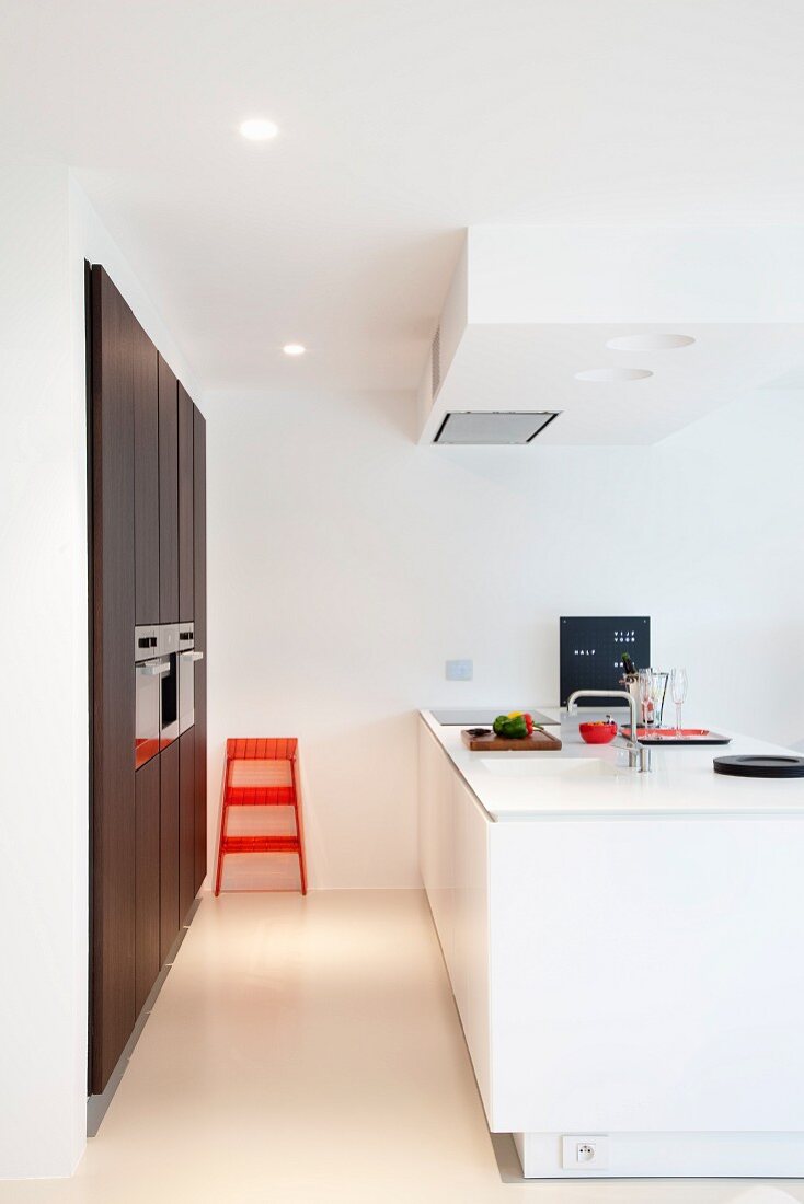 Designer kitchen with white island counter and fitted cupboards with dark doors