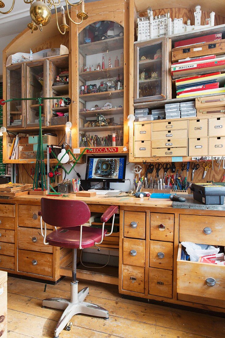 Werkstatt ähnliche Ambiente - Vintage Drehstuhl vor Schubladenschrank, aufgehängte Werkzeugen unter Aufsatz