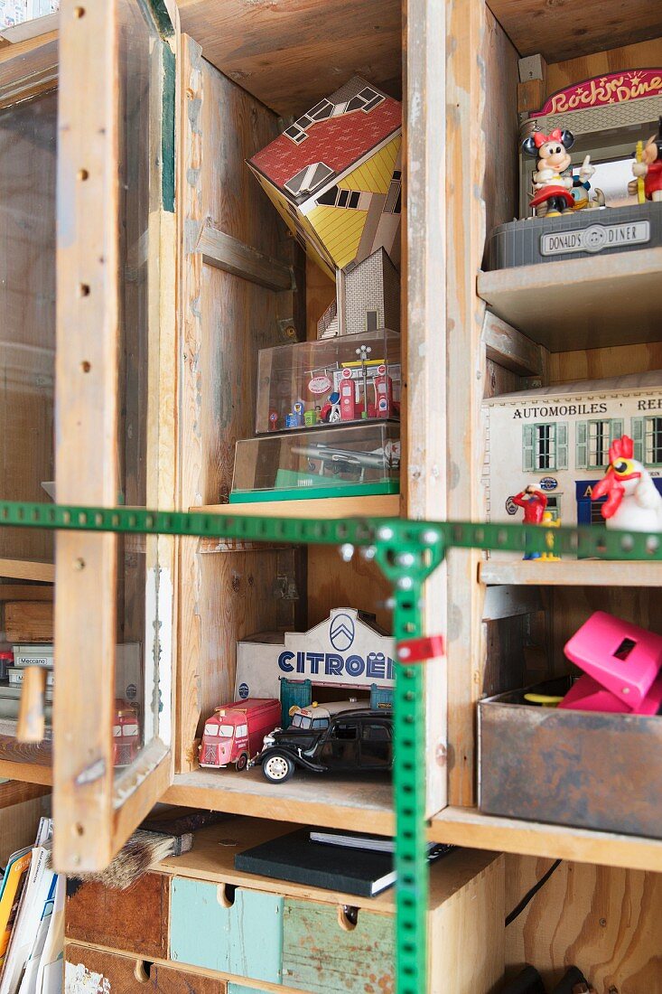 Detail of rustic cupboard with open door and view of vintage toys