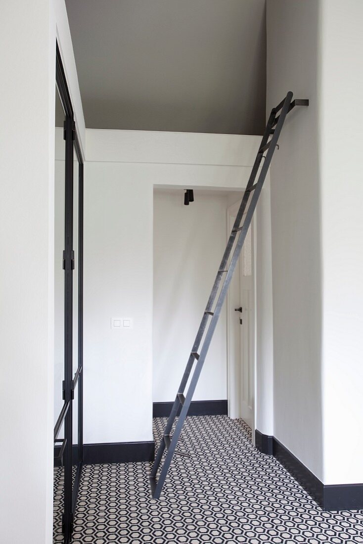 White installation in hallway, ladder attached to wall and retro carpet with black and white geometric patter