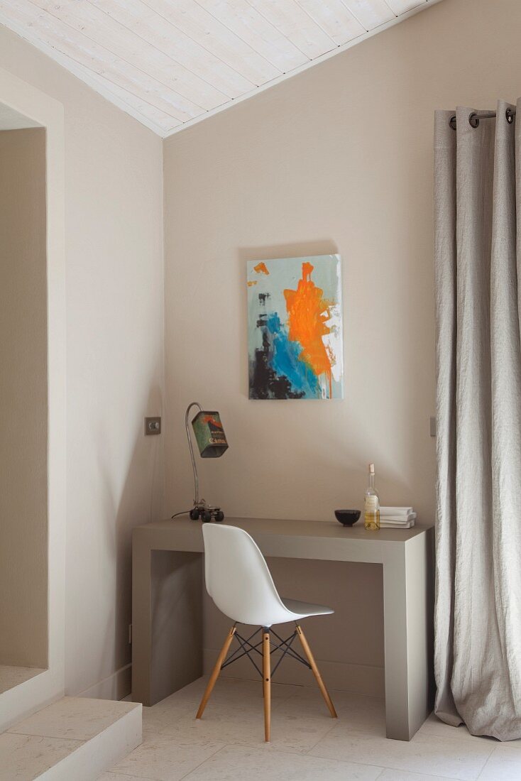 Modern artwork above small workspace with concrete desk and classic chair
