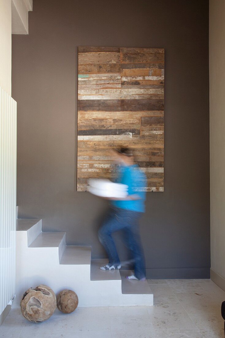 Betontreppe vor modernem Bild auf brauner Wand im Dielenbereich; Mann auf Treppenstufe