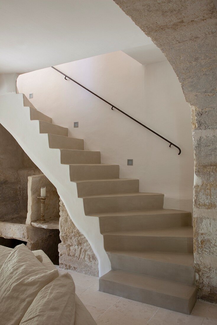 Curved concrete staircase with wrought iron handrail in Provençal stone house