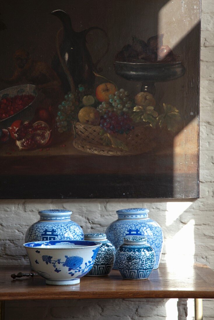 Blau-weiße, asiatische Deckelvasen und Schale, darüber Bild mit Stillleben