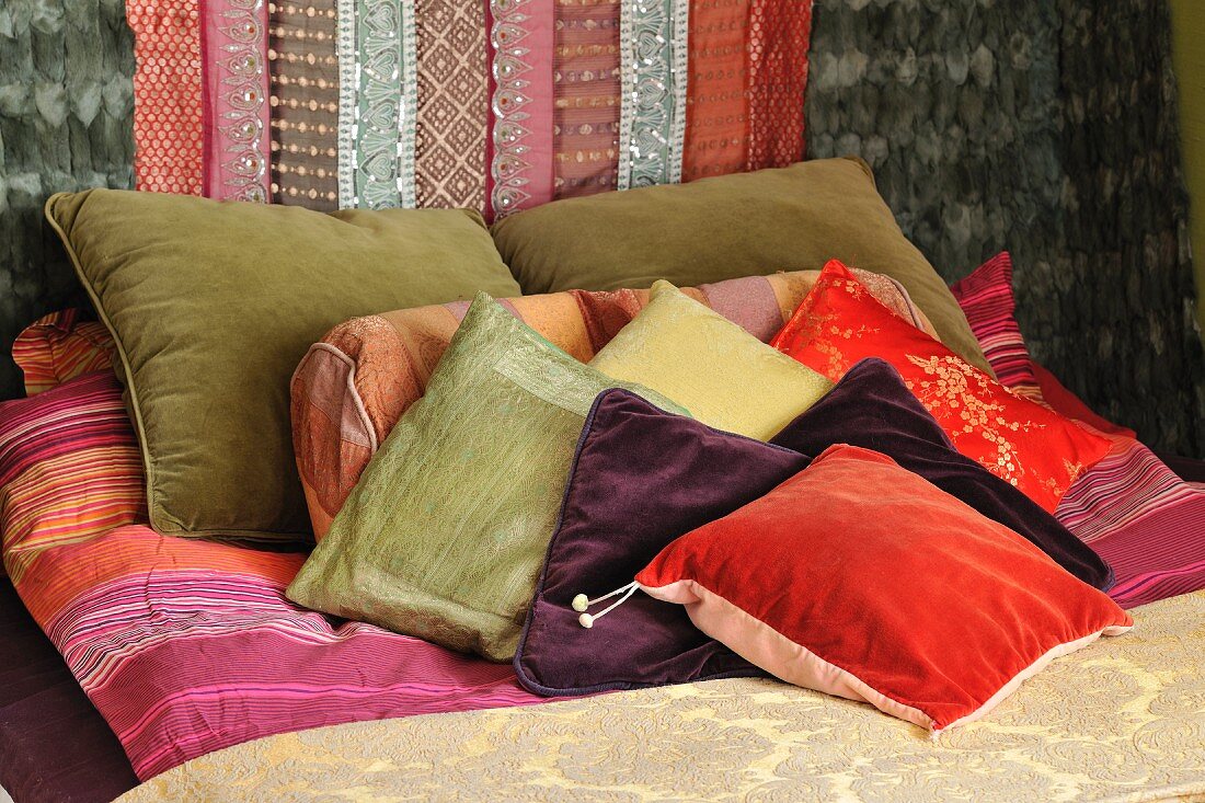 Scatter cushions on bed with brocade bedspread, wall decorated with mink furs, velvet and silk fabrics with sequins