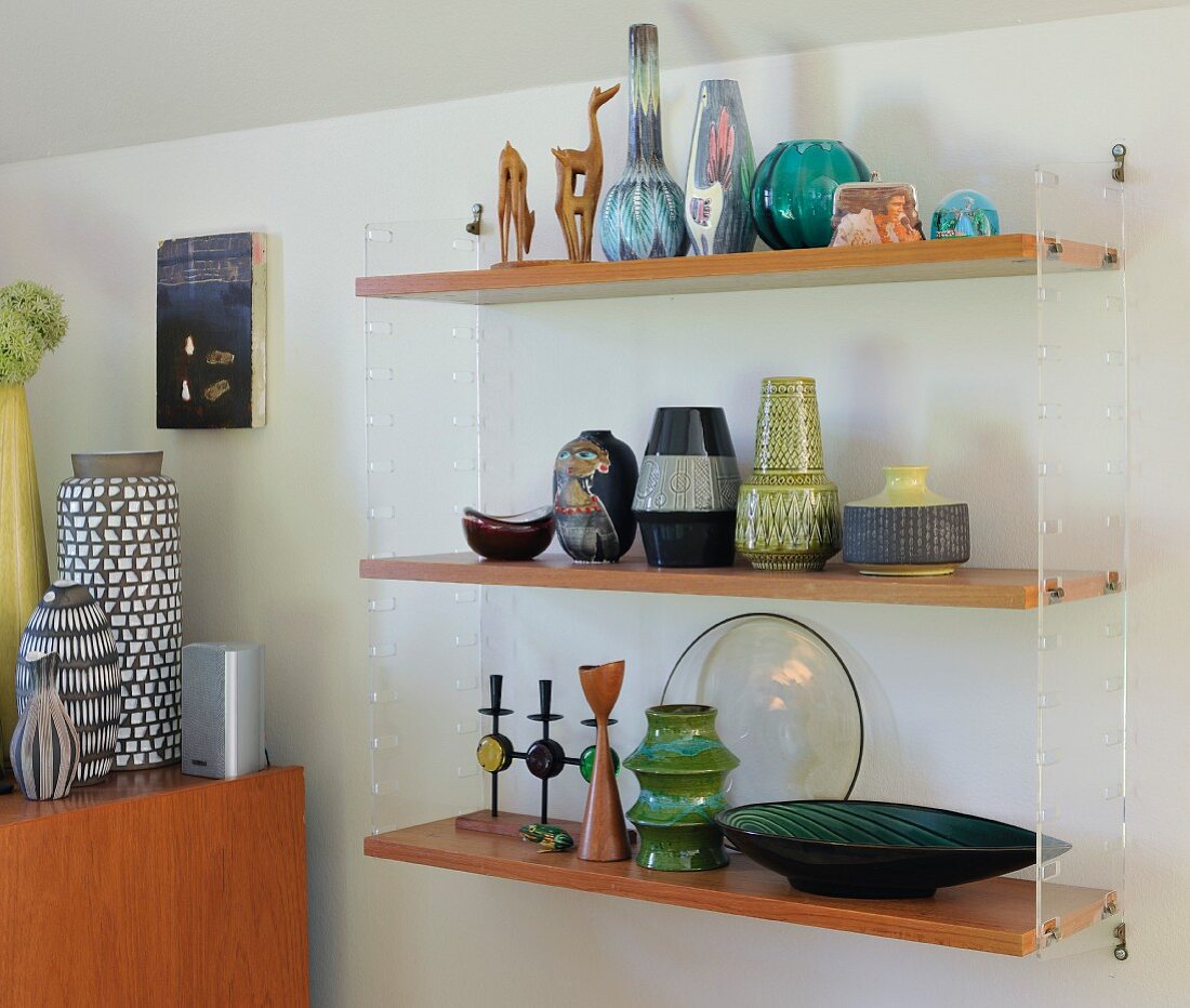 Collection of retro vases on wooden shelves supported by transparent plastic end panels