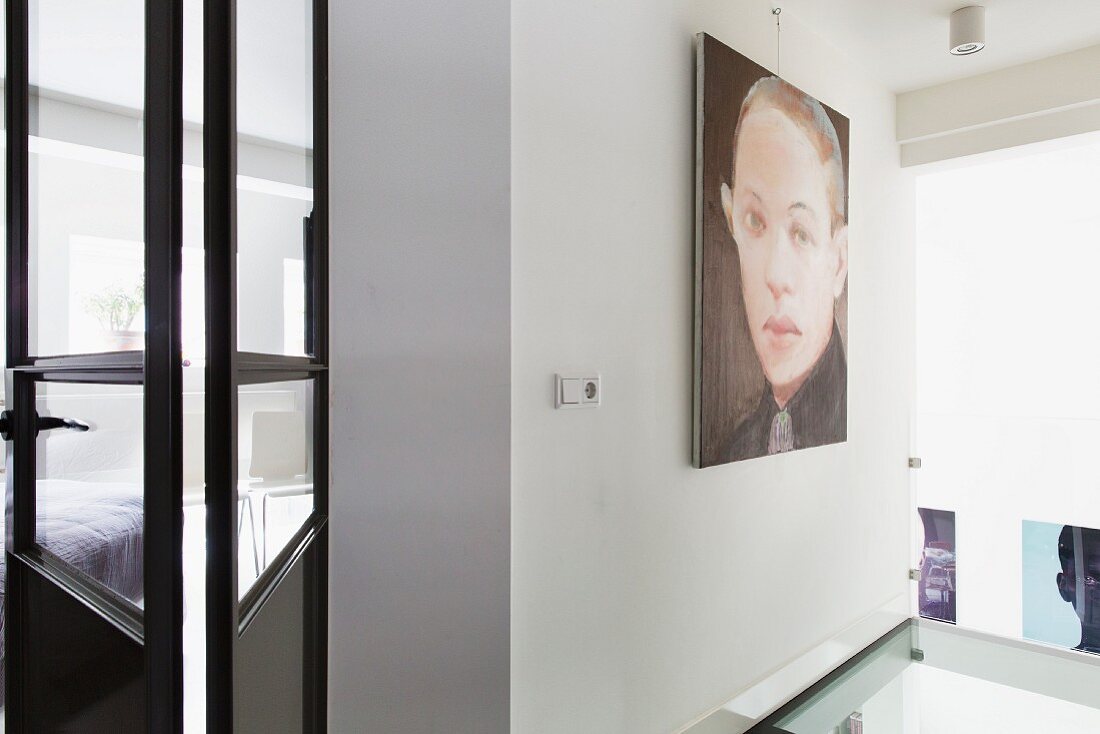 Large portrait on wall next to open, glass and metal door