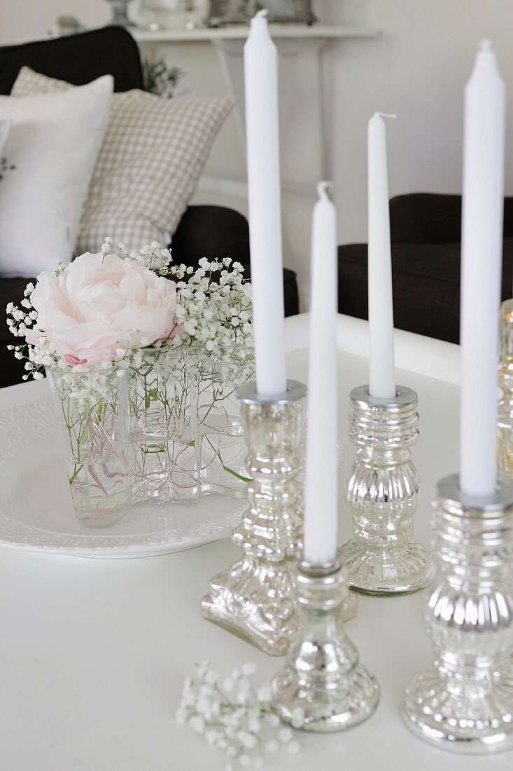 Silber Kerzenhalter mit weissen Kerzen und kleiner Blumenstrauss mit Rose und Schleierkraut