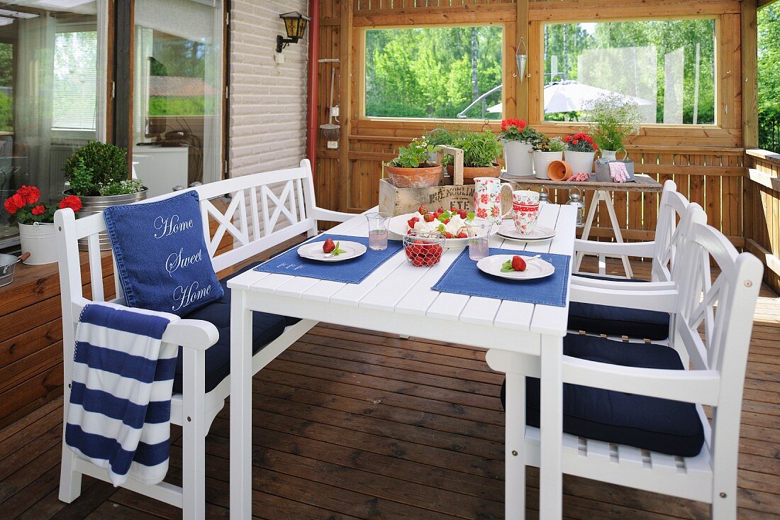 weiße Tisch- und Stuhlgarnitur mit blauen Polstern und Tischsets in der Loggia