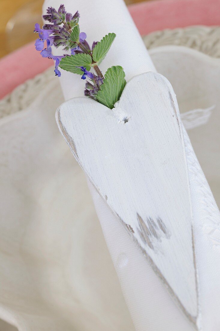 Table decoration with white wooden love-heart and sprig of flowers on place setting
