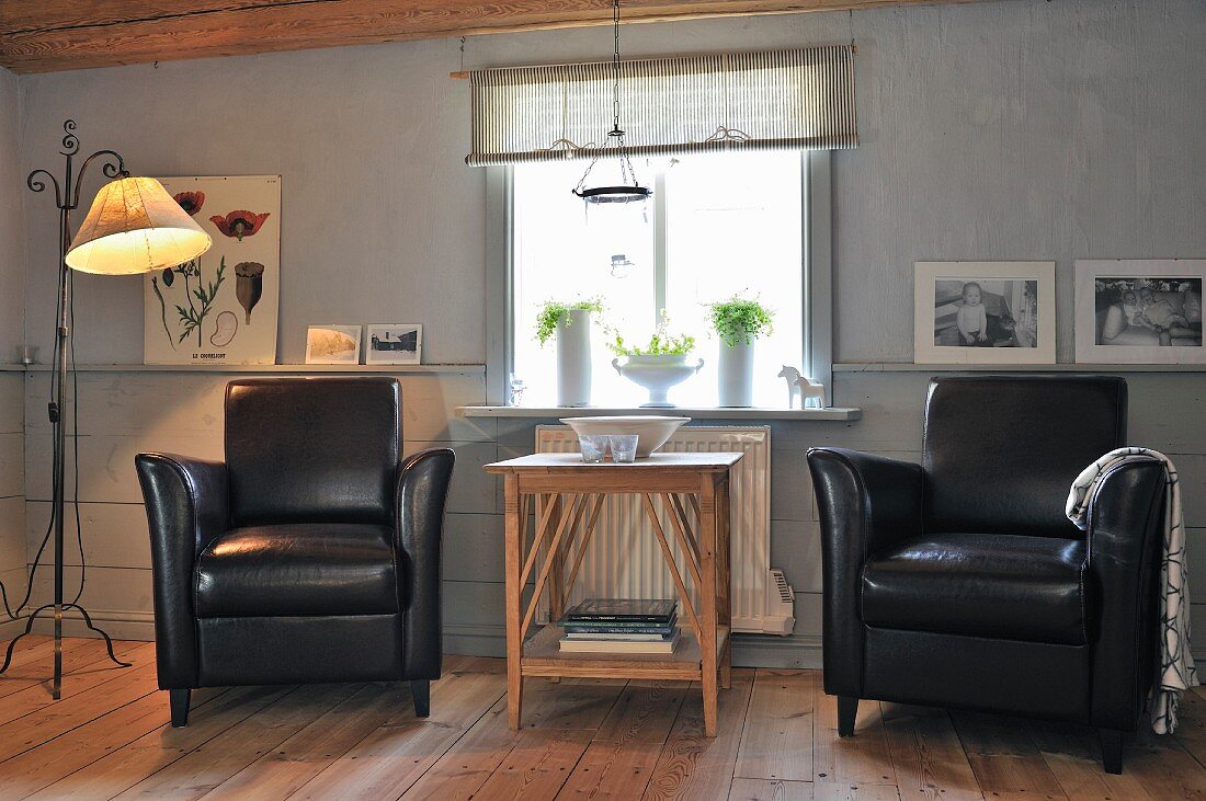 Two black leather armchair flanking delicate wooden table in comfortable, Scandinavian, country-house interior