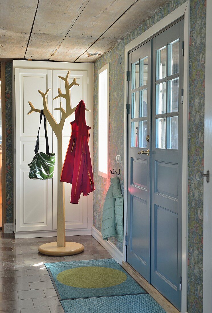 Rustic foyer with double front door and stylised tree as coat stand