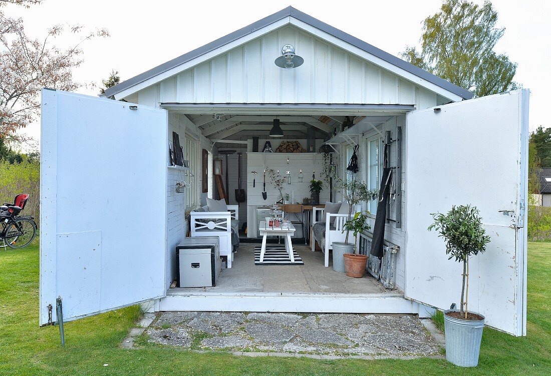 Blick in umgenutzte Garage mit gemütlicher Vintage-Möblierung und zur Aufbewahrung von Gartengeräten