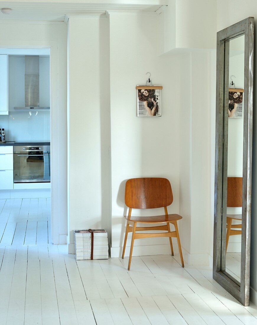 Hallway with minimalist furnishings with full-length mirror and wooden chair on white wooden floor