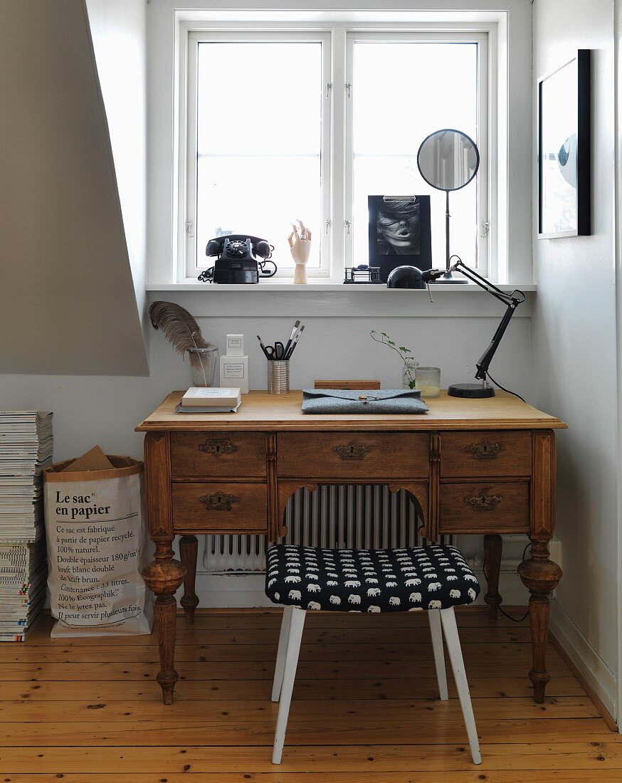 Vintage desk and vintage stool below window with rotary dial telephone on windowsill