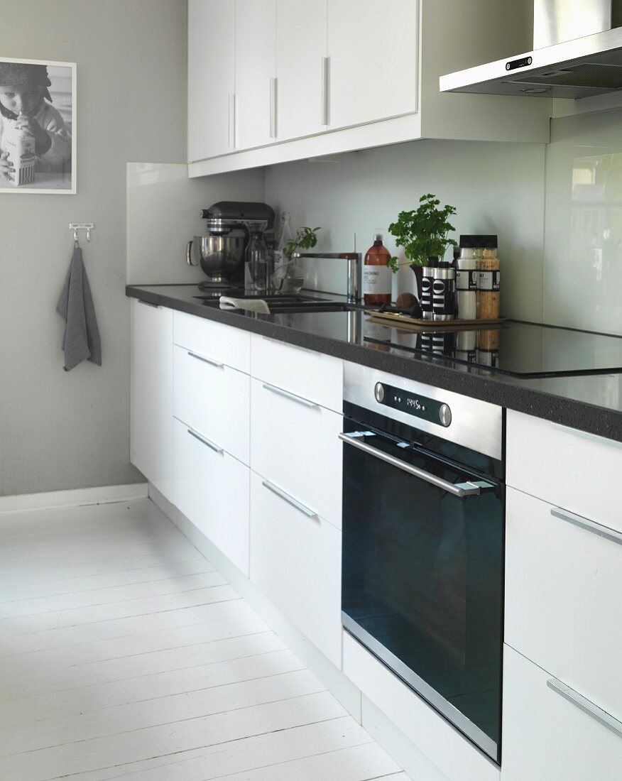 weiße Designerküche mit Spritzschutz und weiß gestrichenem Dielenboden