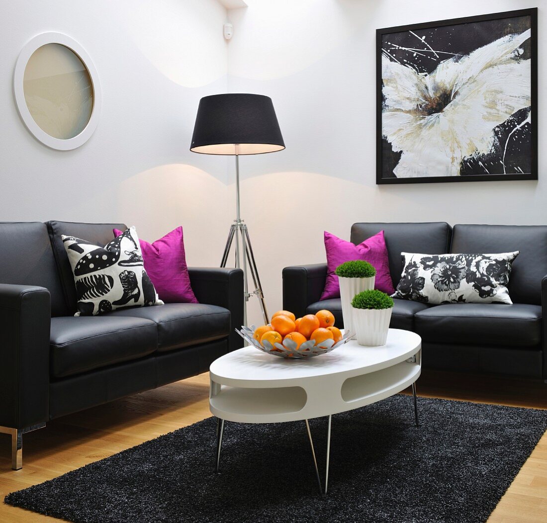 Lounge area with white, oval, retro table and simple, black leather sofas