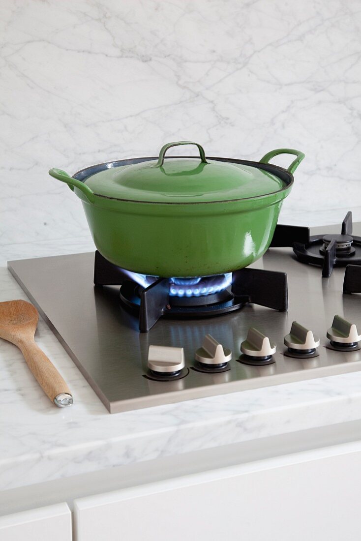 Green enamel pan on gas hob and marble worksurface