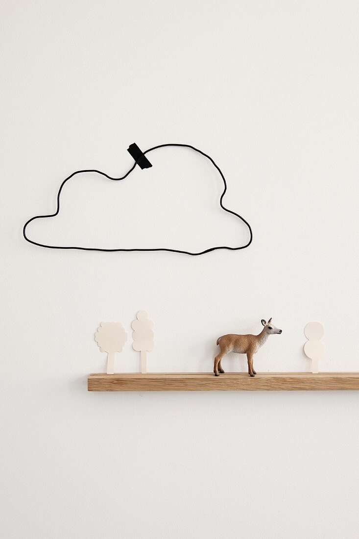 Schmales Wandbord mit Rehfigur und ausgeschnittenen Papierbäumen, darüber eine selbstgebastelte Draht-Wolke mit Masking-Tape